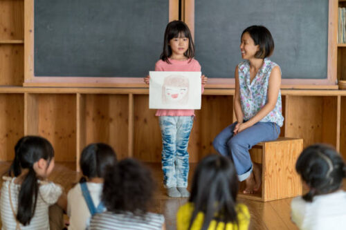 女の子が自分の書いた絵を教室で発表している