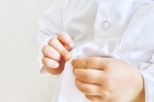 子供がブラウスのボタンを閉めてる